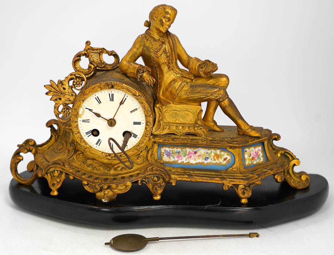 A 19th century figurative ormolu mantel clock, with floral porcelain panels, on stand with key and pendulum, stand approximately 39cm wide. Condition - clock dial cracked, clock untested as working